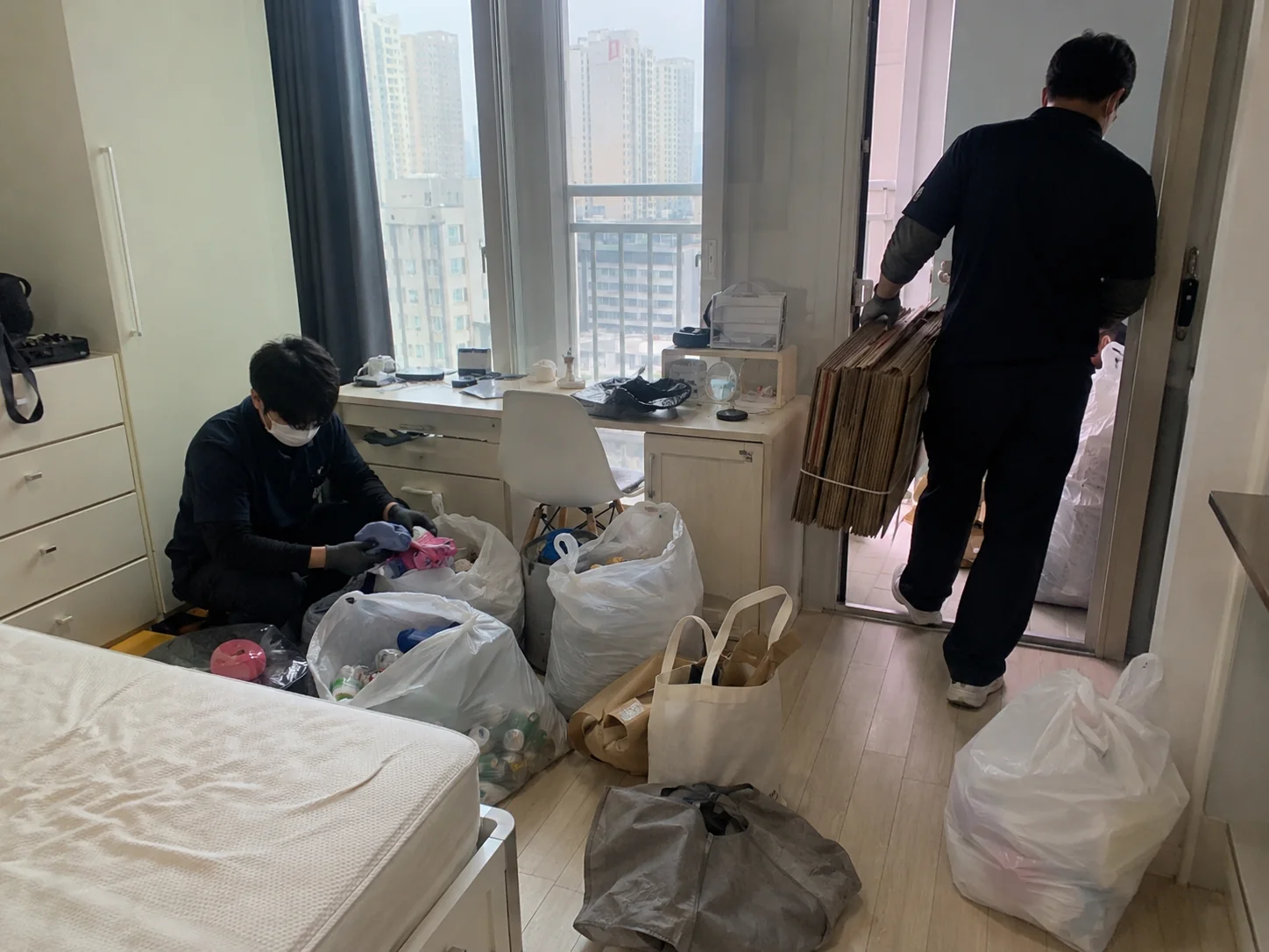침실에 쌓인 폐기물을 정리하는 작업자